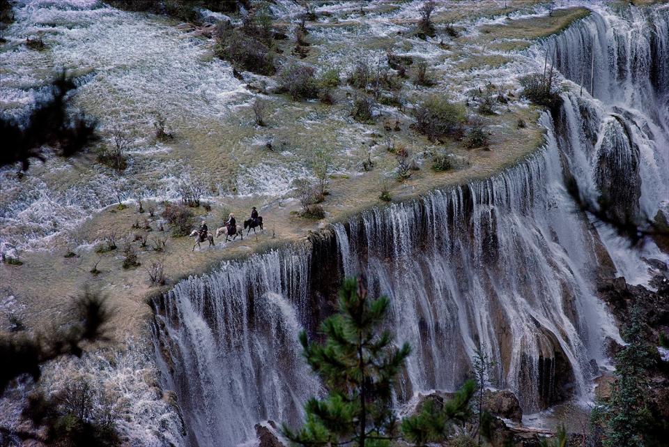 Cary Wolinsky perched in a mountain tree to snap this photo of Tibetan herdsmen headed to market crossing the crest of the beautiful Jiuzhaigou Pearl Shoal Waterfall, Sichuan, China, on Oct. 8, 1984.