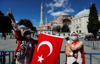 People carry a Turkish flag outside the Hagia Sophia or Ayasofya, a UNESCO World Heritage Site, which was a Byzantine cathedral before being converted into a mosque and currently a museum, in Istanbul