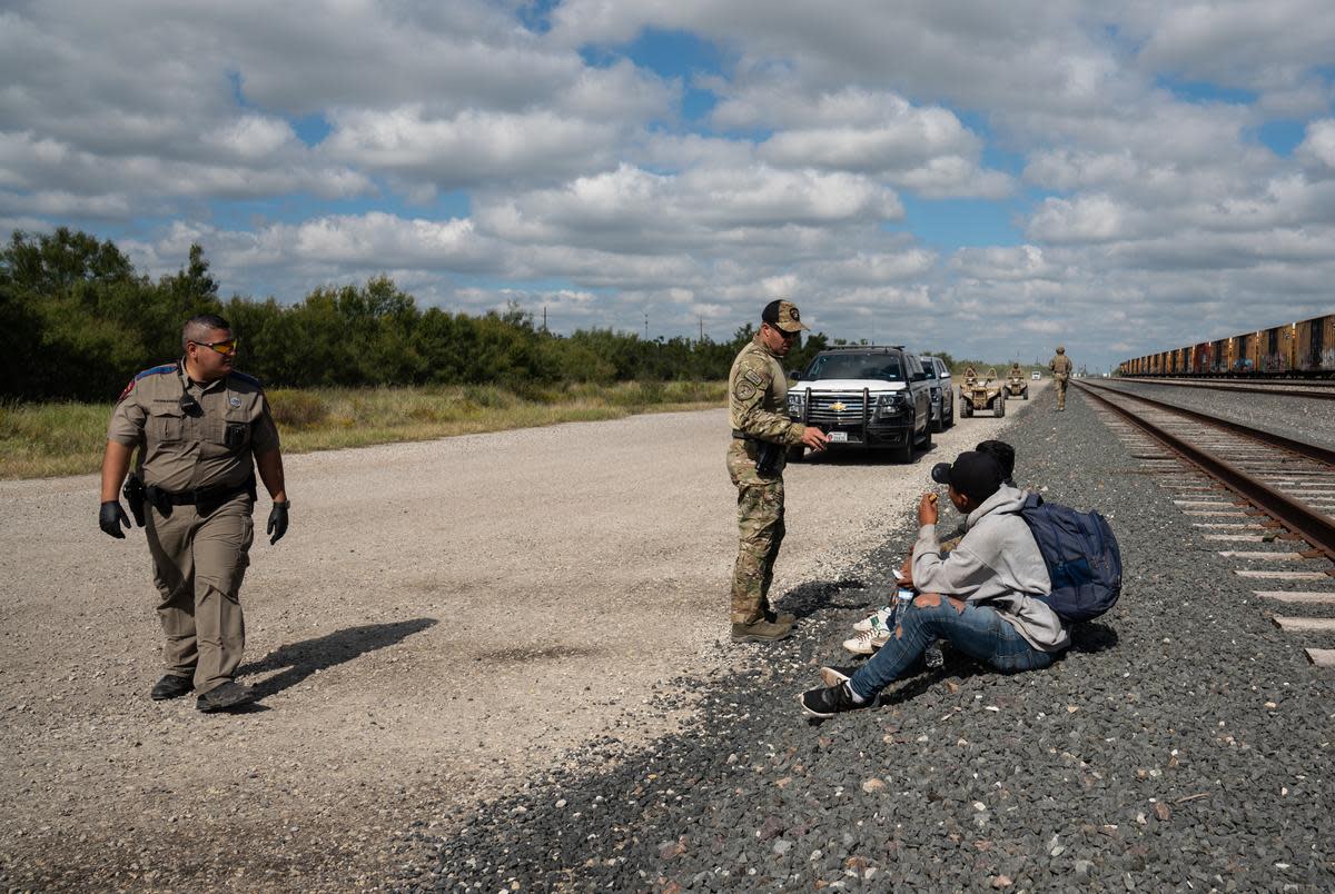 Department of Public Safety agents oversee a group of three undocumented migrants as they continue the process of arresting them after they were caught in private property as part of Operation Lone Star in Kinney County near Brackettville, on Nov. 8, 2021.