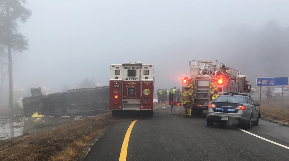 This photo provided by Virginia State Police emergency responders at the scene after a charter bus overturned on an Interstate 95 exit near Kingwood, Va., Tuesday, March 19, 2019. Virginia State Police said in a statement that the Tao's Travel Inc. bus with 57 people aboard overturned Tuesday morning in Prince George County near Kingwood while traveling from Florida to New York. (Virginia State Police via AP)