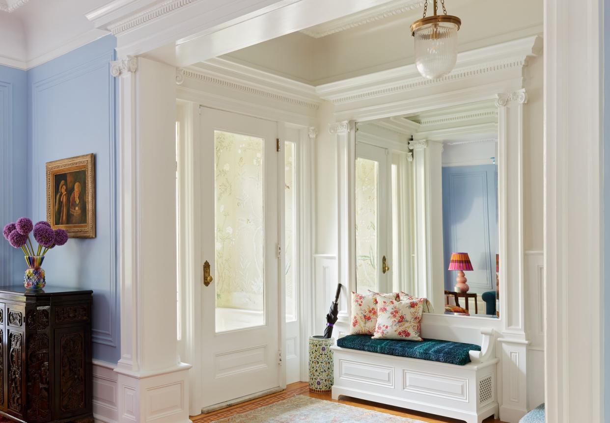  An entryway with a wallpaper, a cozy seating and white walls. 