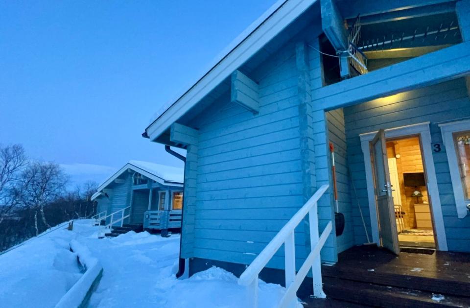 The blue cabins are side by side in Lapland, with snow covering the ground.