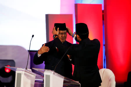 Indonesia's vice presidential candidate Sandiaga Uno arranges national cap, called peci, of presidential candidate Prabowo Subianto during a televised debate with his opponent Joko Widodo (not pictured) in Jakarta, Indonesia January 17, 2019. REUTERS/Willy Kurniawan