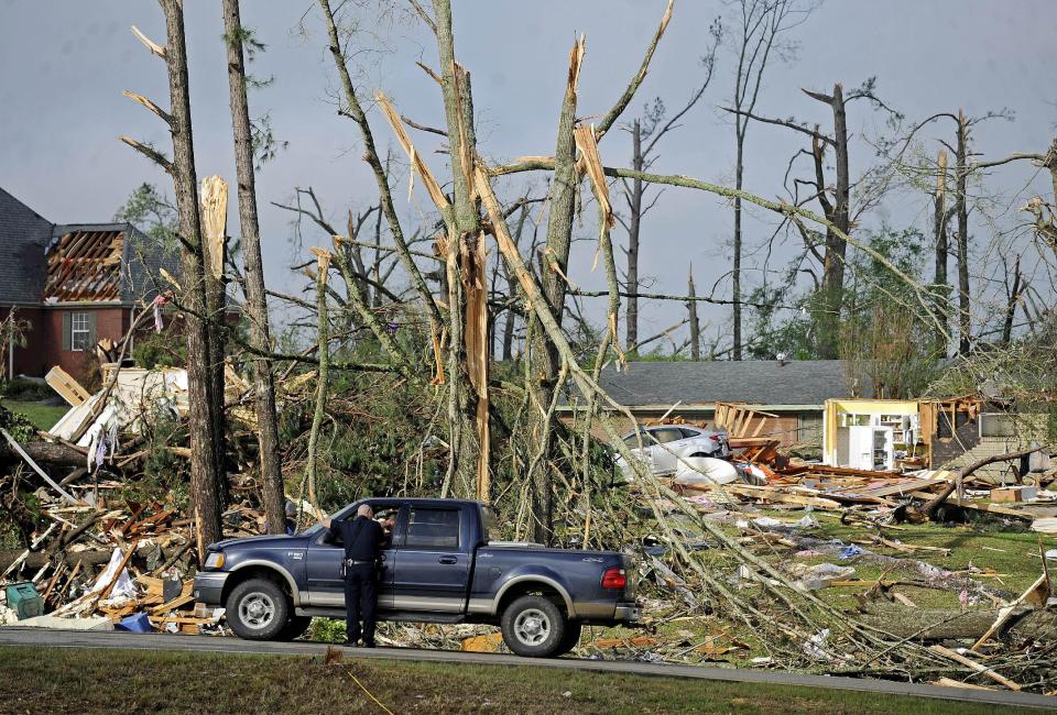 A police officer directs traffic in front of damaged homes on Clayton Avenue in Tupelo, Miss., Tuesday, April 29, 2014. A dangerous storm system that spawned a chain of deadly tornadoes over three days flattened homes and businesses, forced frightened residents in more than half a dozen states to take cover and left tens of thousands in the dark Tuesday. (AP Photo/Thomas Graning)