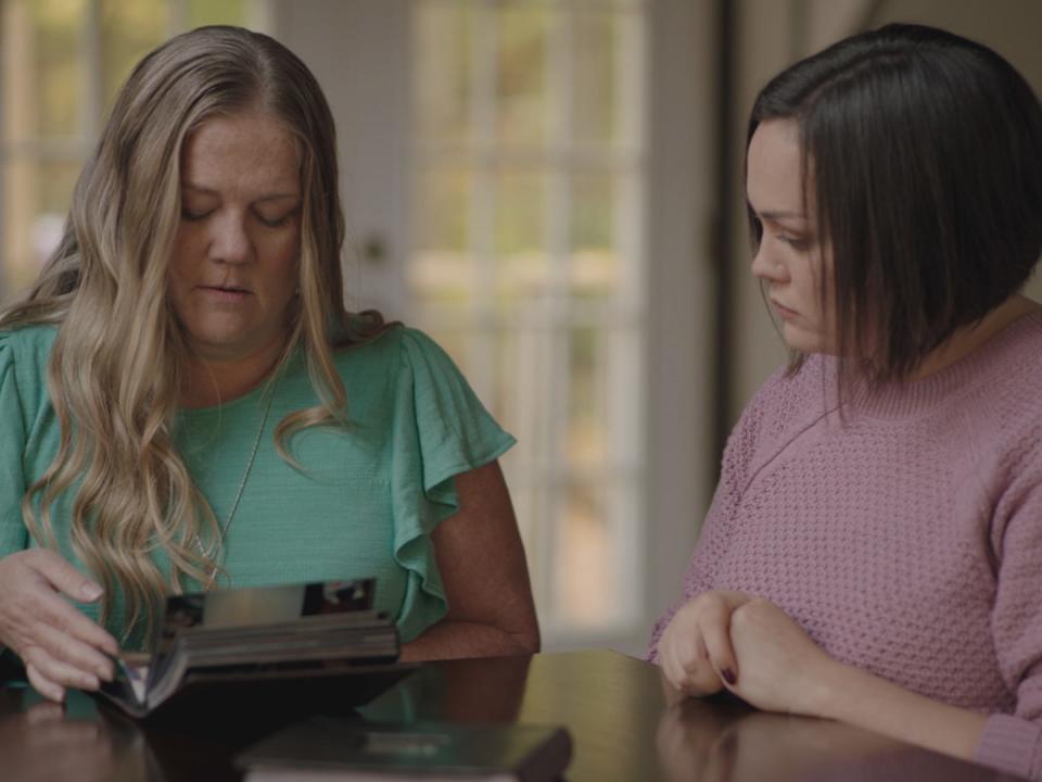 Kathy Durbin, in a blue top, and Ruthy Heiler, looking through a photo album.