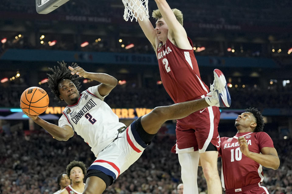 UConn guard Tristen Newton (2) passes around Alabama forward Grant Nelson (2) during the second half of the NCAA college basketball game at the Final Four, Saturday, April 6, 2024, in Glendale, Ariz. (AP Photo/David J. Phillip)