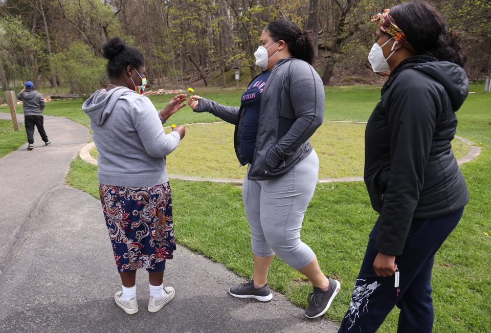 Destiny Roque gives Lydia Sellers dandelions while on a field trip to the Powder Mills Park during the Webster Day Habilitation program run by Heritage Christian Services. Roque works with individuals who attend the program.