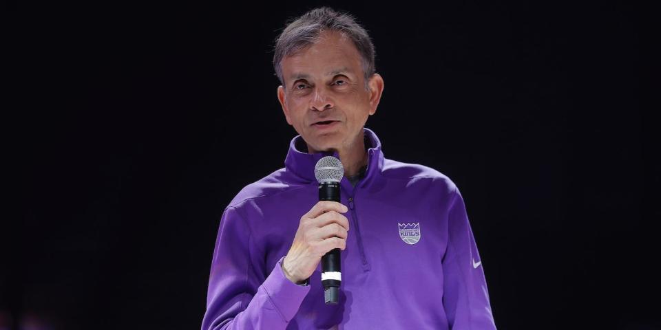 Vivek Ranadive speaks on a microphone in front of a dark arena.