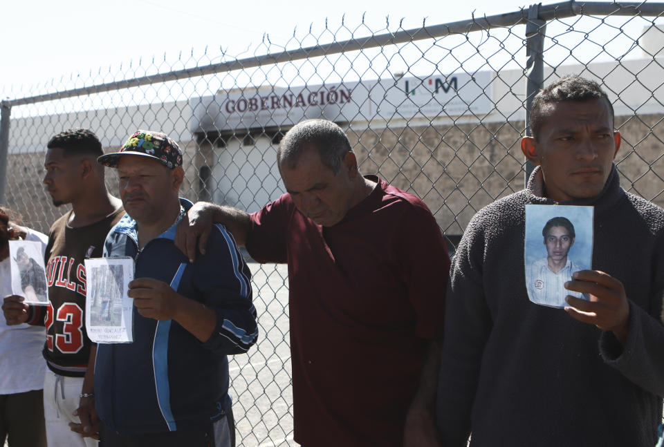 ARCHIVO - Migrantes, principalmente de Venezuela, muestran fotos de quienes murieron en un incendio en el centro de detención de migrantes mexicano detrás de ellos, durante una vigilia de oración a las afueras del mismo en Ciudad Juárez, México, el 27 de abril de 2023. Cuatro meses después del incendio en un centro de detención de migrantes de la frontera en el que murieron 40 personas, varios supervivientes siguen viviendo en el limbo en un hotel de Ciudad de México, mientras se recuperan de las heridas y en espera de que los responsables sean procesados. (AP Foto/Christian Chávez, Archivo)