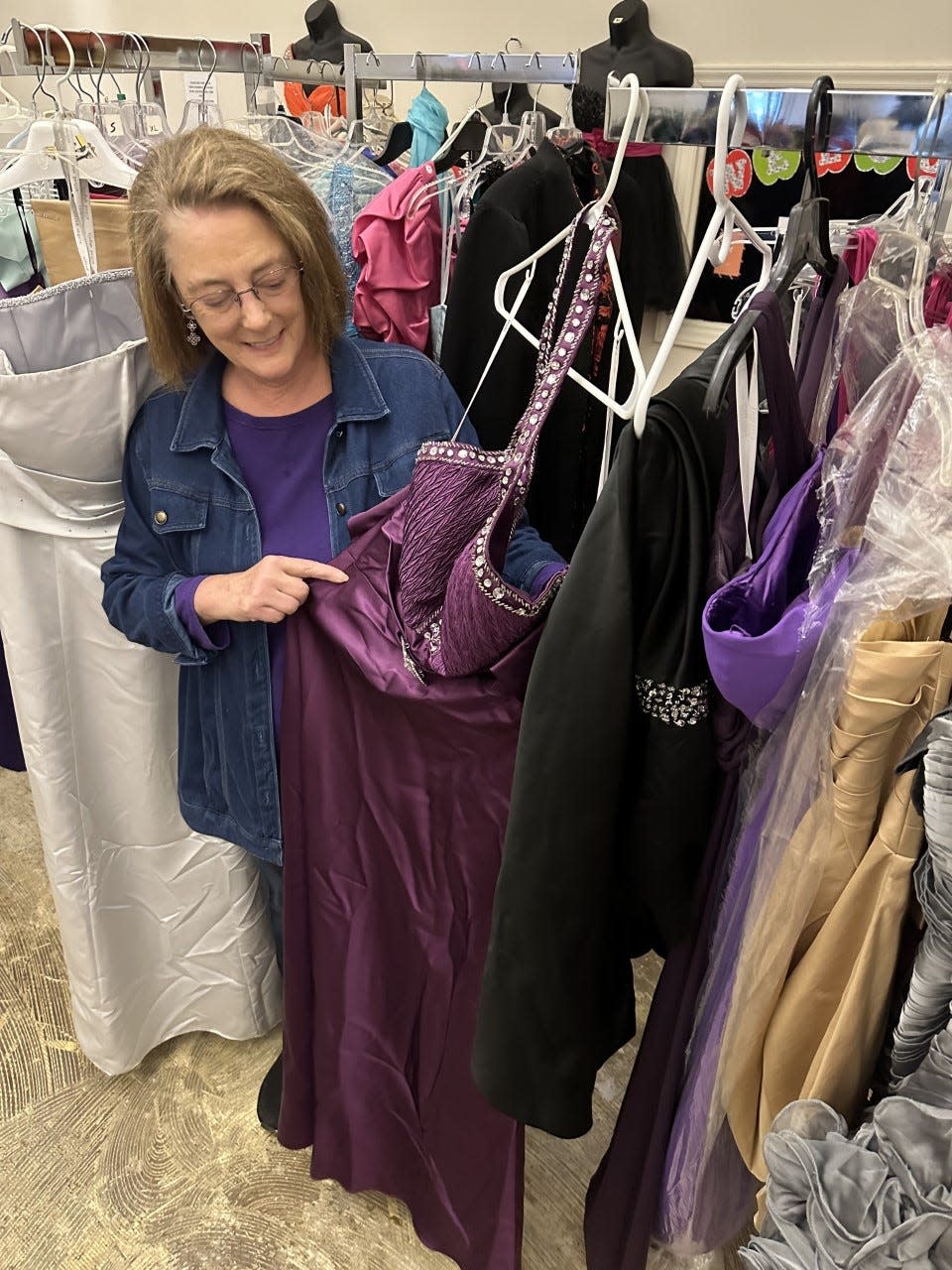 Melanie Burr displays one of the prom dresses available at the Totally Free Clothes Store. The store recently moved to a bigger location and is able to give away thousands of clothes for free each month.