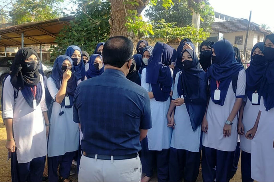 Indian girl students who were barred from entering their classrooms for wearing hijab, a headscarf used by Muslim women, speak to their principal outside the college campus in Udupi, India, Friday, Feb. 4, 2022. Muslim girls wearing hijab are being barred from attending classes at some schools in the southern Indian state of Karnataka, triggering weeks of protests by students. (Bangalore News Photos via AP)