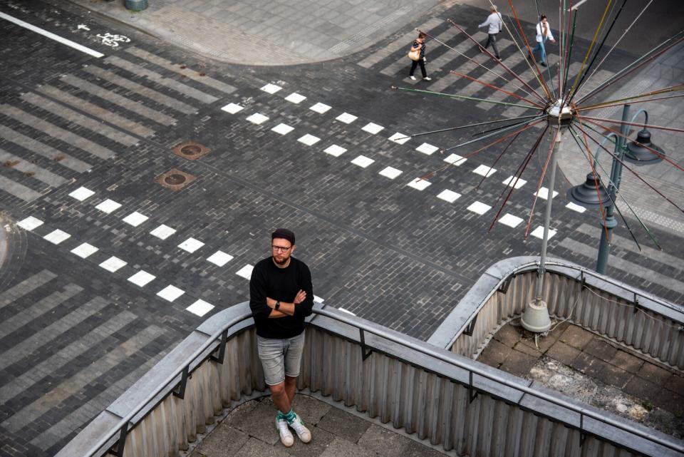 Jonas Spokas standing on a rooftop, as seen above a street