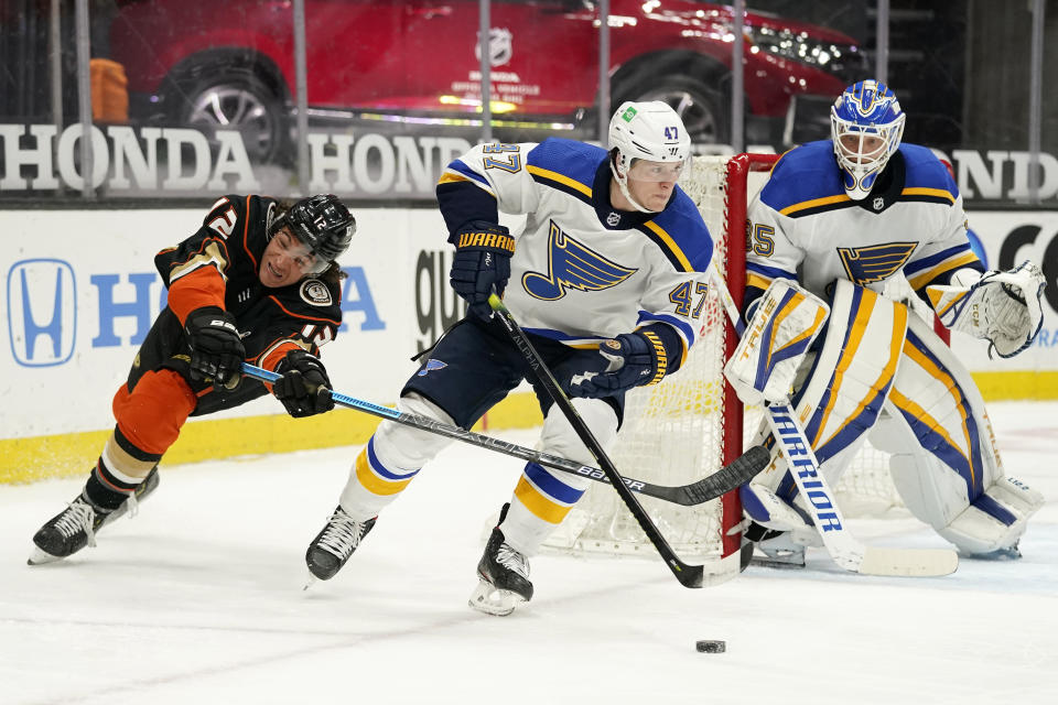 St. Louis Blues defenseman Torey Krug, center, skates with the puck as Anaheim Ducks left wing Sonny Milano, left, reaches in and goaltender Ville Husso watches during the second period of an NHL hockey game Monday, March 1, 2021, in Anaheim, Calif. (AP Photo/Mark J. Terrill)