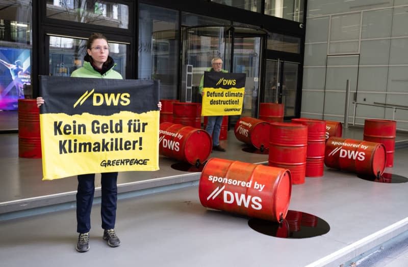 Greenpeace activists protest against investment policy of the DWS Investment's with red oil drums in front of the company's headquarters in Frankfurt. Boris Roessler/dpa