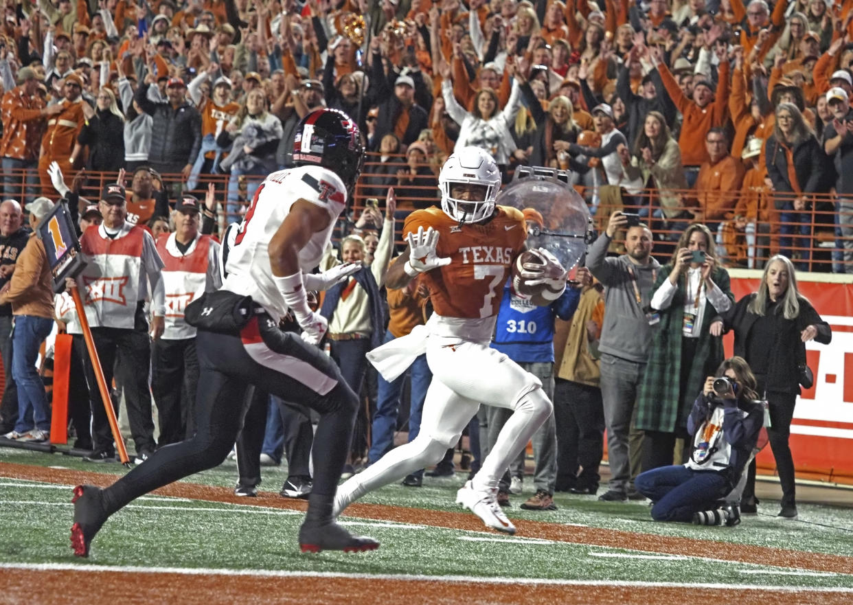 Texas running back Keilan Robinson (7) runs for a touchdown against Texas Tech defensive back C.J. Baskerville, left, during the first half of an NCAA college football game, Friday, Nov. 24, 2023, in Austin, Texas. (AP Photo/Michael Thomas)