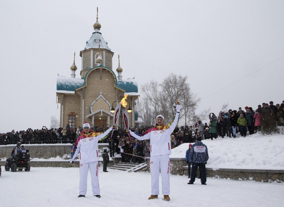 In this photo provided by Olympictorch2014.com, Olympic torch bearers Vyacheslav Kokorin, left, and Konstantin Bakulev hold Olympic torches during the torch relay in Kirov, Russia, Sunday, Jan. 5, 2014. The relay for the Sochi Winter Games, which began on Oct. 7 2013 in Moscow, will pass through many cities that showcase the historical, cultural and ethnic richness of Russia. (AP Photo/Olympictorch2014.com)