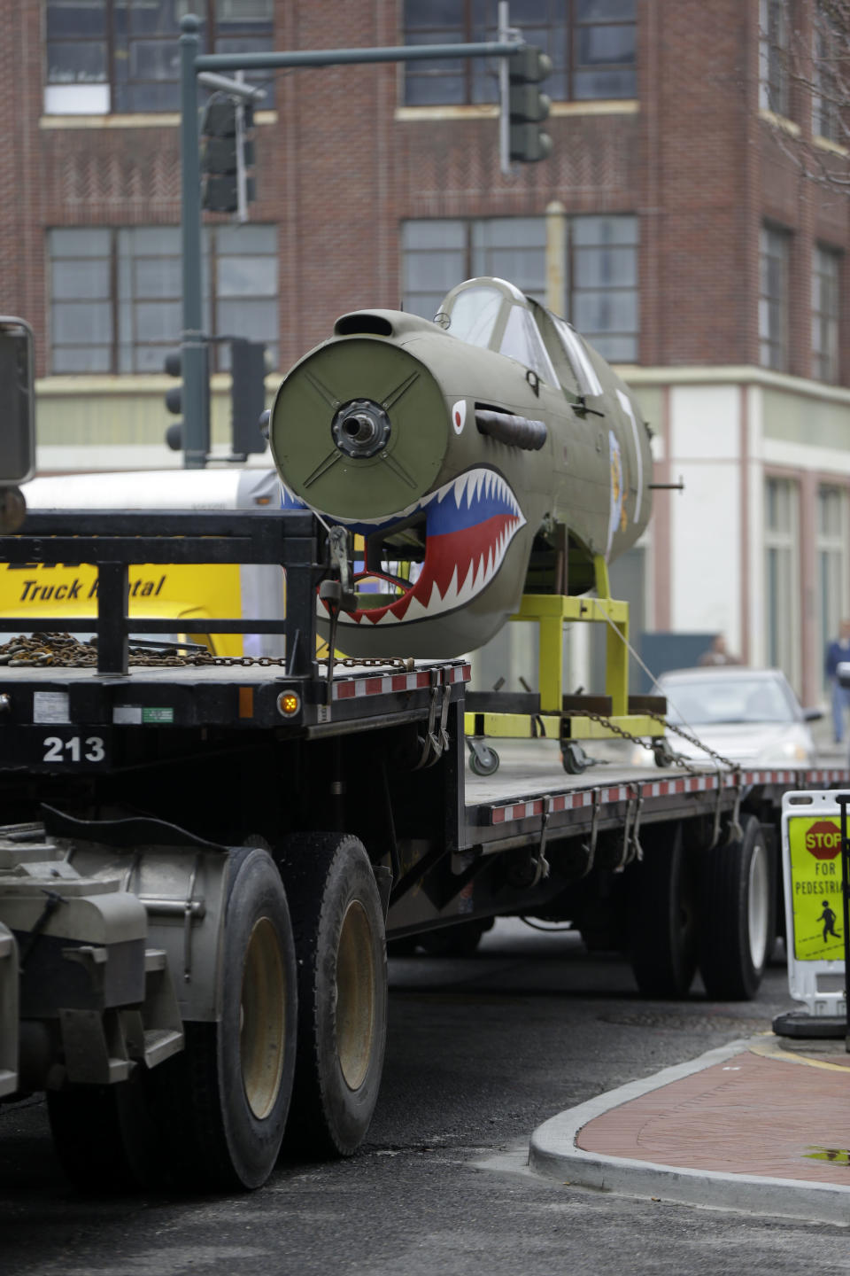A restored P-40 Curtiss Warhawk fighter plane, one of only 32 known remaining in the world, arrives on a flatbed truck for permanent display at the National World War II Museum in New Orleans, Monday, Feb. 3, 2014. The plane, painted in the scheme of the famed Flying Tigers, will be displayed in the museum’s new pavilion, Campaigns of Courage: European and Pacific Theaters. (AP Photo/Gerald Herbert)
