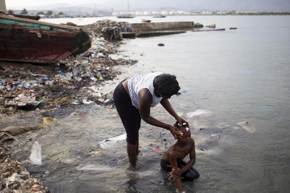 In this Sunday, March 17, 2019 photo, a woman bathes her daughter on the seashore as they get ready for church, at the Warf of Port Cite Soleil in Port-au-Prince, Haiti. (AP Photo/Dieu Nalio Chery)