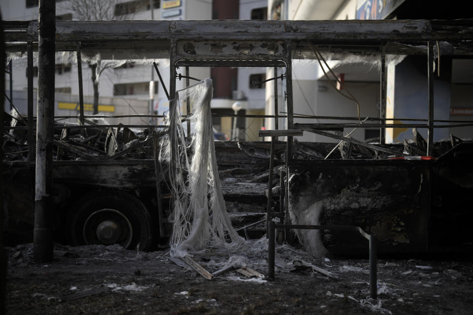 A burned-out bus stands partly beneath a residential building in the district Neukoelln in Berlin, Germany, Tuesday, Jan. 3, 2023. People across Germany on Saturday resumed their tradition of setting off large numbers of fireworks in public places to see in the new year. The bus was set on fire during the New Years celebrations. (AP Photo/Markus Schreiber)