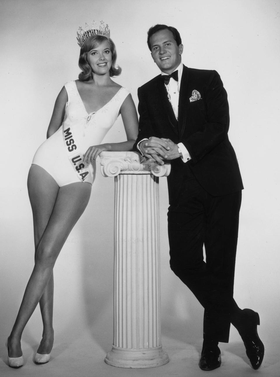 Miss USA 1964 Bobbi Johnson poses with Pat Boone. They both lean on a pillar.