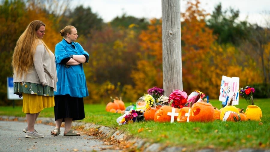 People pay their respects at a makeshift memorial outside a bowling alley, the site of one of this week’s mass shootings, Sunday, Oct. 29, 2023, in Lewiston, Maine. A gunman killed multiple people at the bowling alley and a bar in Lewiston on Wednesday. (AP Photo/Matt Rourke)