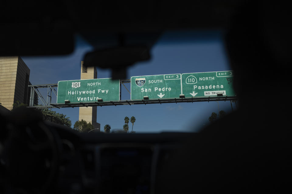 Freeway signs are seen through the windshield of a car as Arusyak Martirosyan and Dennis Cotek, investigators with the Los Angeles County Public Administrator's office, travel to an apartment to conduct a search in Los Angeles, Thursday, Nov. 16, 2023, after a tenant died in the hospital with no apparent next of kin. (AP Photo/Jae C. Hong)