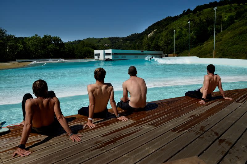 FILE PHOTO: Members of Germany's national surf team watch surfers ride in Wave Garden, a giant pool that generates surfable waves, in the Basque town of Aizarnabazaba