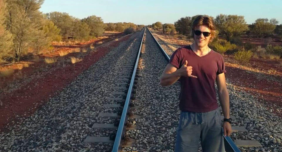 Backpacker Theo Hayez poses for a photo on train tracks.