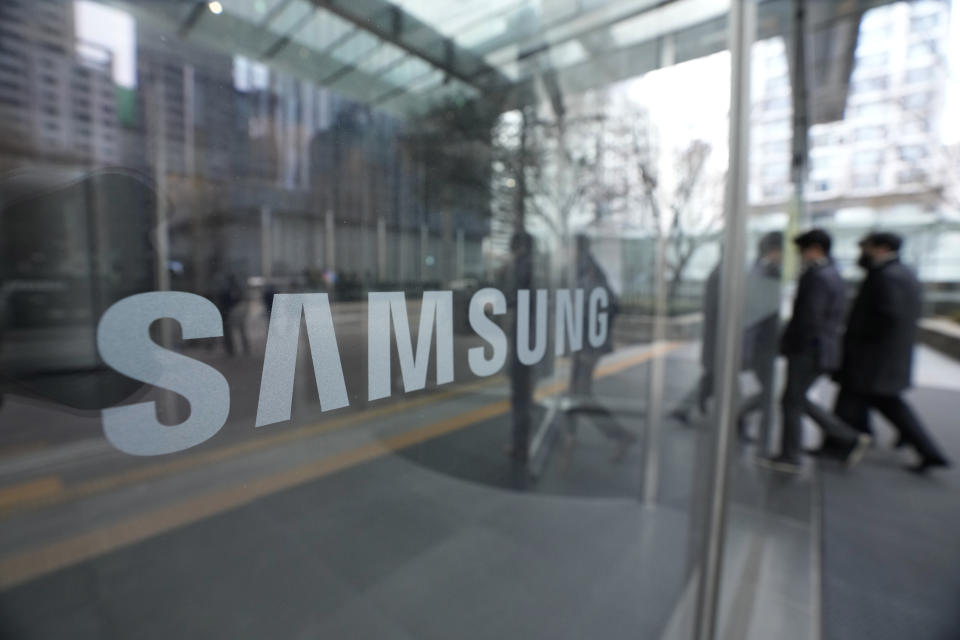 Employees walk past a logo of the Samsung Electronics Co. at its office in Seoul, South Korea, Tuesday, Jan. 31, 2023. Samsung Electronics said Tuesday its profit for the last quarter plummeted nearly 70% as a weak global economy depressed demands for its consumer electronics products and computer memory chips. (AP Photo/Ahn Young-joon)