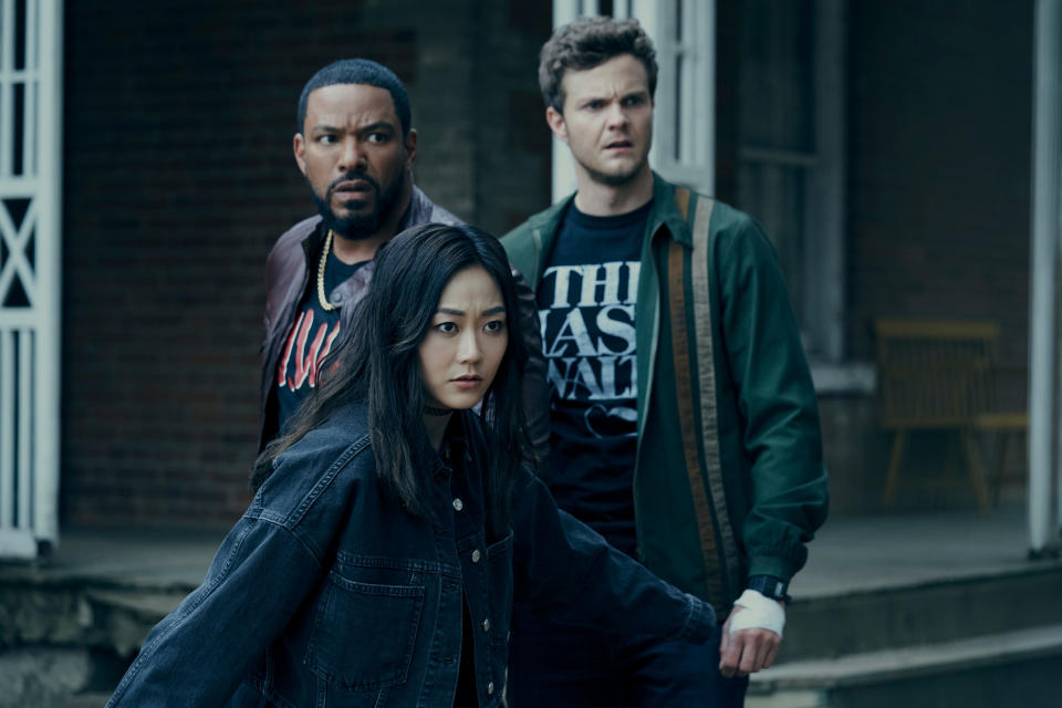 Three characters, including Hughie, played by Jack Quaid, stand together in a defensive stance in front of a building