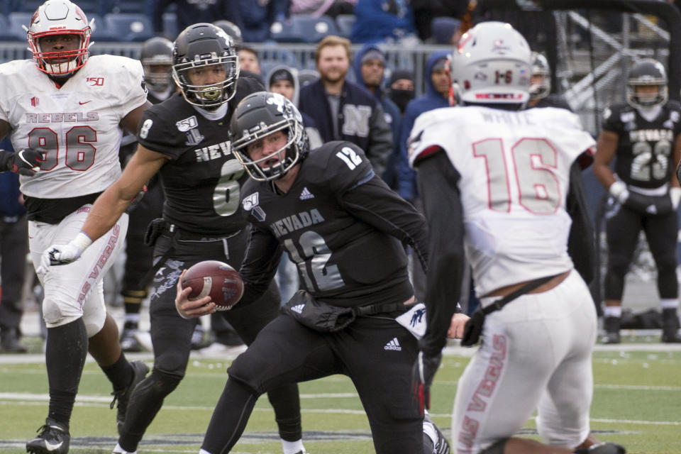 FILE - In this Nov. 30, 2019, file photo, Nevada quarterback Carson Strong (12) cuts back as UNLV linebacker Javin White (16) closes in during the second half of an NCAA college football game in Reno, Nev. The Las Vegas Raiders were the first team to play inside Allegiant Stadium. But the UNLV Rebels will be the first team to play with fans inside the $2 billion dollar venue, when they host in-state rival Nevada on Saturday, Oct. 31, 2020. (AP Photo/Tom R. Smedes, File)