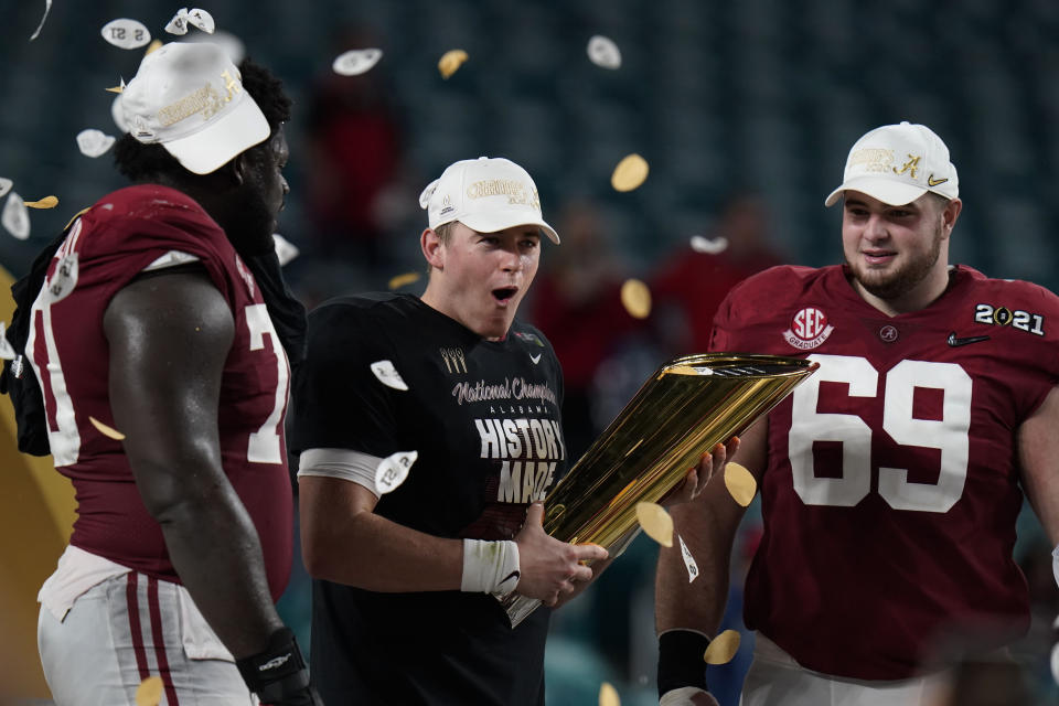 Alabama quarterback Mac Jones, middle, offensive linemen Alex Leatherwood, left, and Landon Dickerson, right, celebrate with the trophy, after their win against Ohio State in an NCAA College Football Playoff national championship game, Tuesday, Jan. 12, 2021, in Miami Gardens, Fla. Alabama won 52-24. (AP Photo/Chris O'Meara)