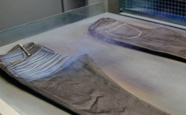 <p>A laser removes a fine layer of indigo pigment from the surface of a pair of jeans to create a worn-in look. Photo: Whitney Bauck/Fashionista</p>