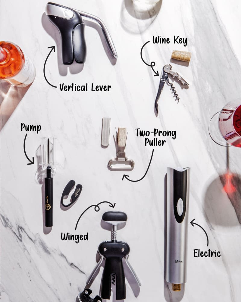 six different tools for opening a wine bottle on a marble surface with glasses of wine