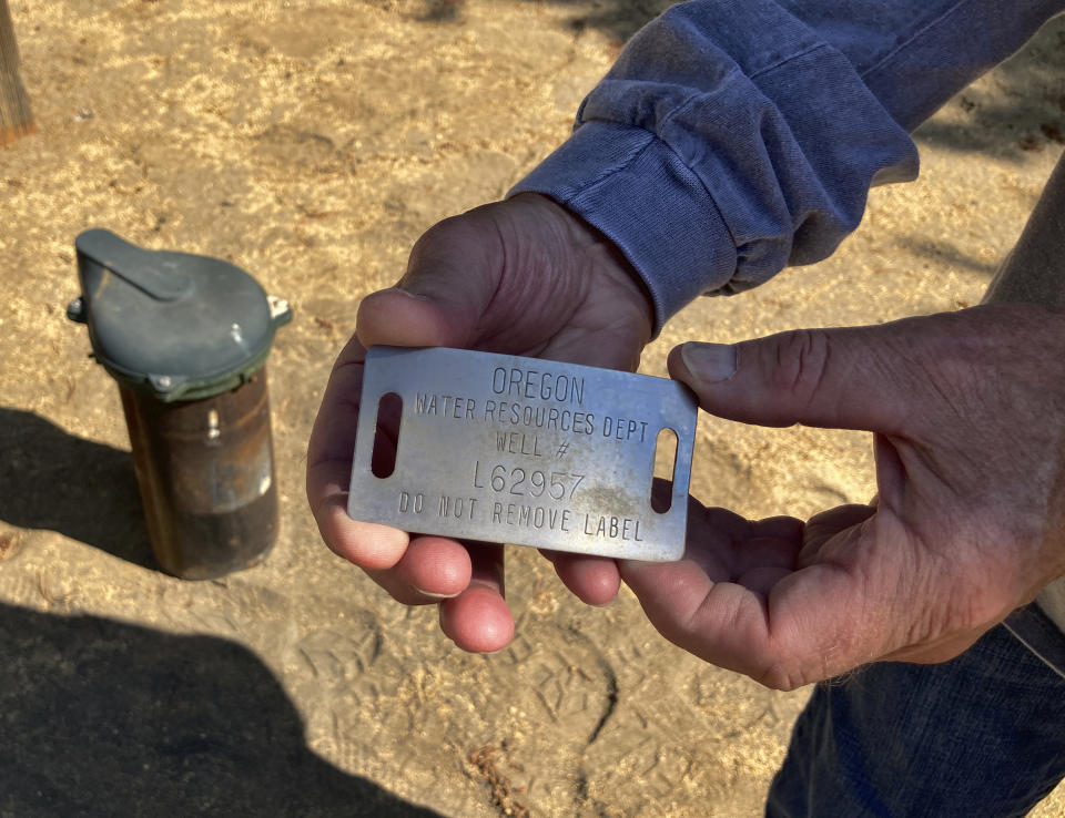 Jim Hooper holds the tag from his well in La Pine, Ore., on Aug. 26, 2021. The well number was checked against a database to determine when it was drilled and other details. Sheriff's deputies busted an illegal marijuana grow a block away recently and another, bigger grow had been nearby, using water from the same aquifer that the neighborhood uses. (AP Photo/Andrew Selsky)