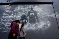 People walk past a mural before the public memorial for NBA great Kobe Bryant, his daughter and seven others killed in a helicopter crash, at the Staples Center in Los Angeles