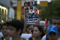 Manifestantes antigubernamentales portan un cartel con fotos de fallecidos durante las protestas con la leyenda "Hérores de la Libertad" durante una marcha en Caracas, Venezuela, el miércoles 16 de abril de 2014. T(AP Photo/Ramon Espinosa). (AP Photo/Ramon Espinosa)