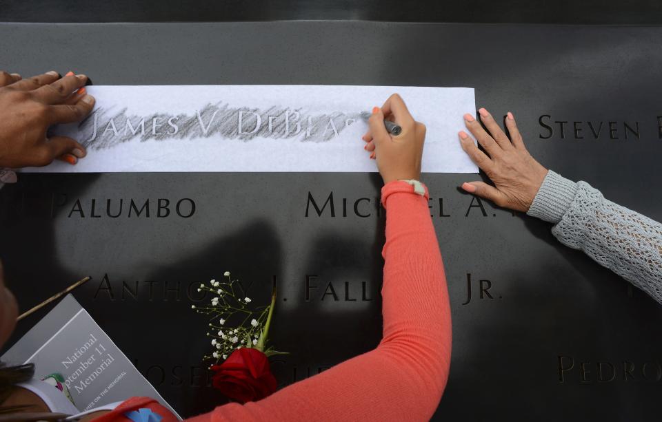 Members of the DeBlase family make a rubbing of their lost loved one James V. DeBlase during memorial observances held at the site of the World Trade Center in New York, September 11, 2014. (REUTERS/Robert Sabo/Pool)