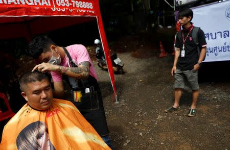 A volunteer cuts hair for a rescue worker near the Tham Luang cave complex, where 12 schoolboys and their soccer coach are trapped inside a flooded cave, in the northern province of Chiang Rai, Thailand, July 7, 2018. REUTERS/Soe Zeya Tun