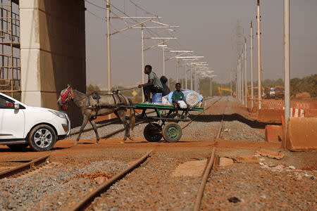 People ride a horse-drawn cart across the new railway tracks for a high speed rail in Mbao, on the outskirts of Dakar, Senegal February 12, 2019. Picture taken February 12, 2019. REUTERS/Zohra Bensemra