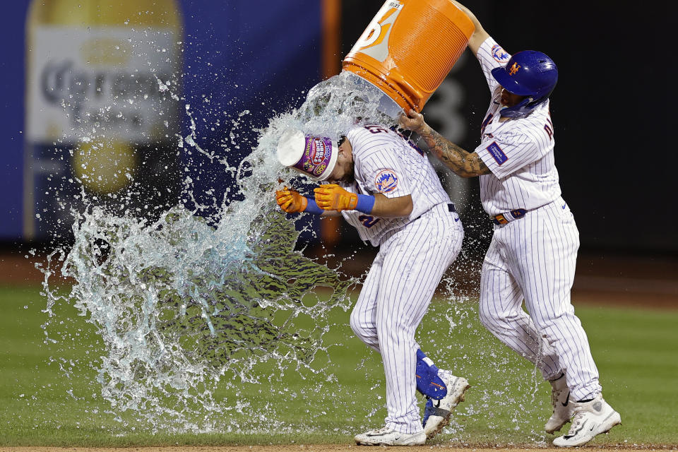 New York Mets' Francisco Alvarez, right, dumps water onto DJ Stewart after Stewart was hit by a pitch with the bases loaded to drive in the winning run against the Texas Rangers during the 10th inning of a baseball game Wednesday, Aug. 30, 2023, in New York. The Mets won 6-5. (AP Photo/Adam Hunger)