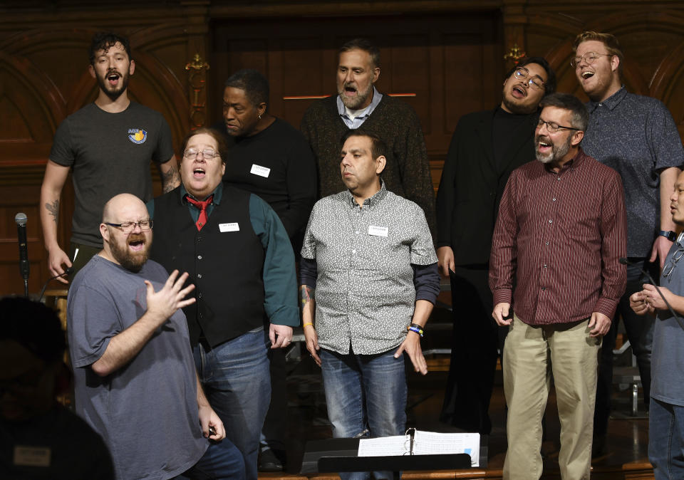 Joey Young, assistant artistic director of the Out Loud Colorado Springs Men's Chorus, bottom left, leads part of the group during a rehearsal for its Christmas program in Colorado Springs, Colo., on Wednesday, Nov. 30, 2022. (AP Photo/Thomas Peipert)