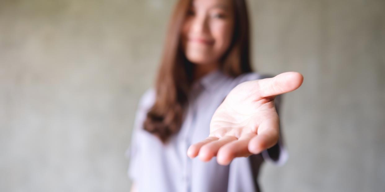 Blurred image of a young woman with reaching hand kindness