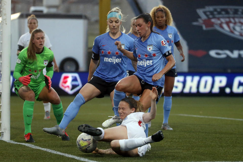 Reign's Kristen McNabb, foreground, kicks the ball as Chicago Red Stars' Julie Ertz, center, and Vanessa DiBernardo, right, defend during the first half of an NWSL Challenge Cup soccer match at Zions Bank Stadium, Saturday, July 18, 2020, in Herriman, Utah. (AP Photo/Rick Bowmer)