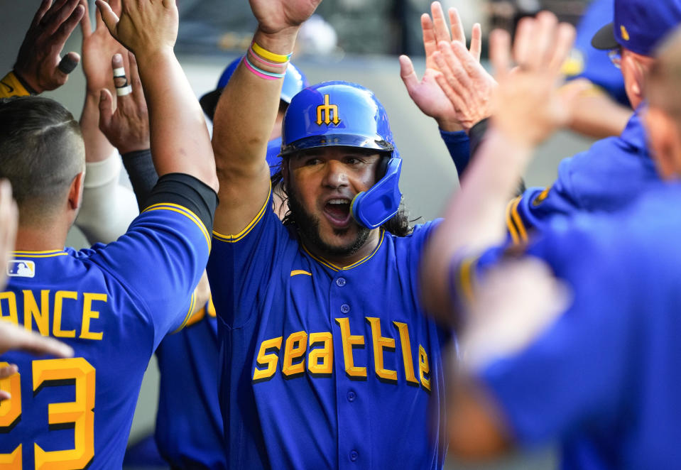 Seattle Mariners' Eugenio Suarez is greeted in the dugout after scoring on a two-run double by Dylan Moore against the Detroit Tigers during the fifth inning of a baseball game Friday, July 14, 2023, in Seattle. (AP Photo/Lindsey Wasson)