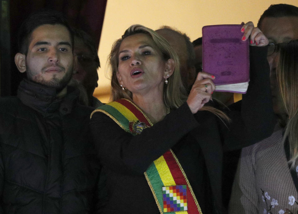Bolivia's second Senate Vice President and opposition politician Jeanine Anez, center, wearing the Presidential sash and holding a Bible, addresses the crowd from the balcony of the Quemado palace after she declared herself interim president of the country, in La Paz, Bolivia, Tuesday, Nov. 12, 2019. (AP Photo/Juan Karita)