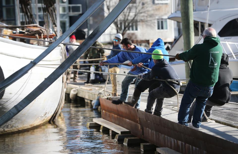 A crew works in sync to balance the Spirit of Massachusetts as a crane lifts it from the Kennebunk River on Nov. 28, 2023. The ship will join a new Pilot House Restaurant on land.