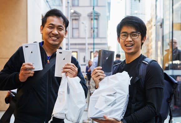 Two customers holding up new iPhones on launch day