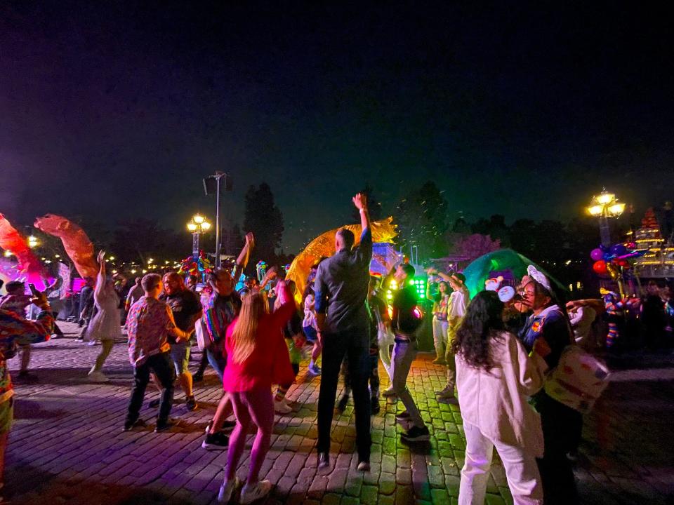 crowds dancing under rainbow lights at night