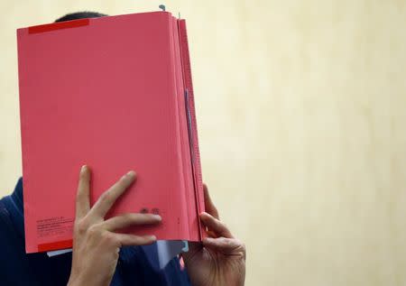 Daniel K., who is accused of having committed a cyber attack against Deutsche Telekom, covers his face as he enters a courtroom before the verdict is announced in Cologne, Germany July 28, 2017. REUTERS/Thilo Schmuelgen